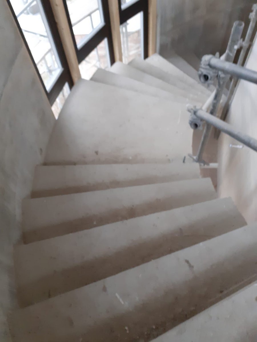 Helles Treppenhaus mit Betonstufen und großen Fenstern